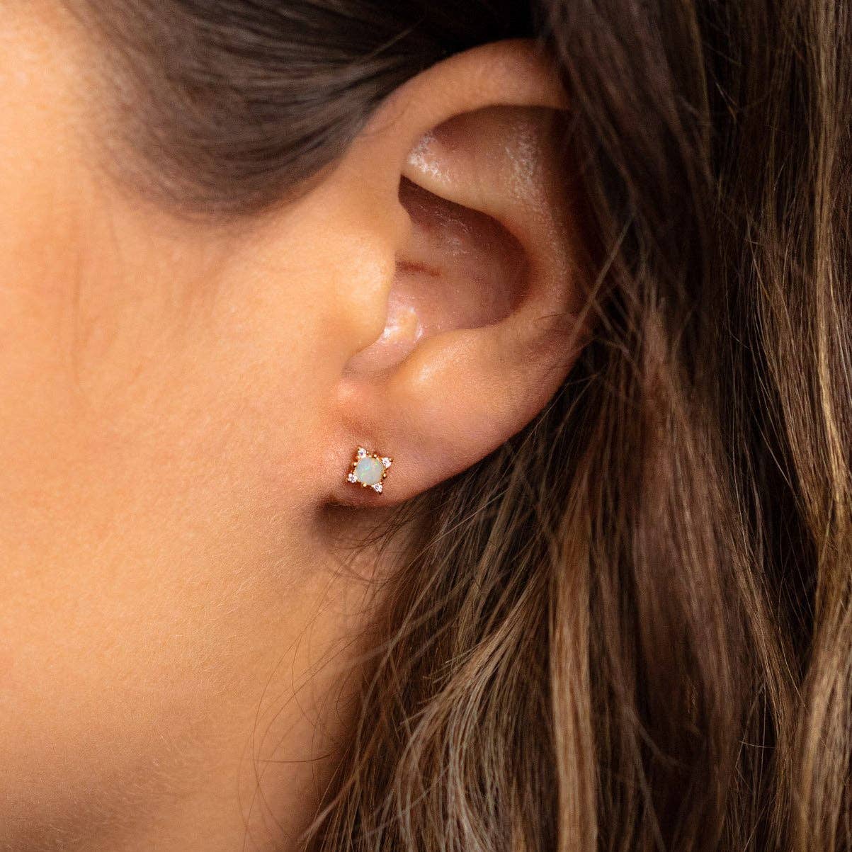 Close-up of an ear wearing a star-shaped earring with brown hair.