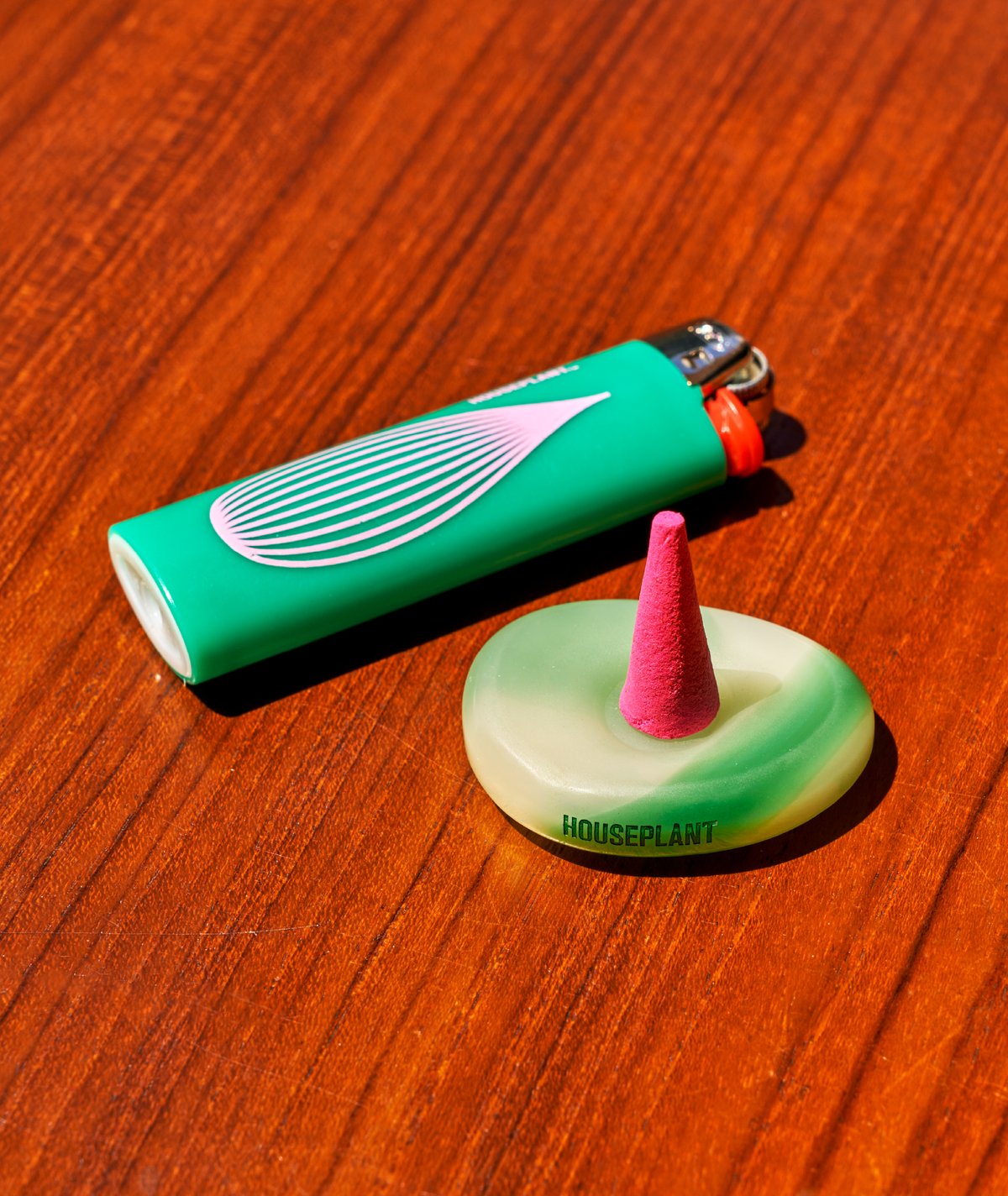 Green lighter and pink incense cone on a wooden surface