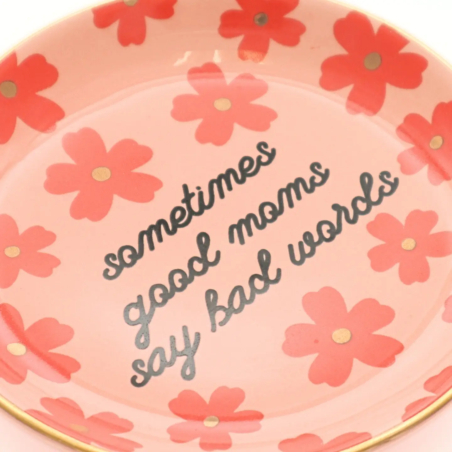 Decorative plate with floral design and humorous text on a pink background