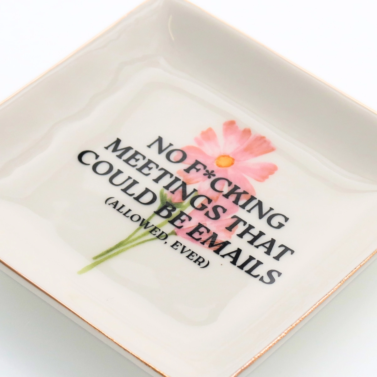 Square ceramic plate with floral design and text on a white background