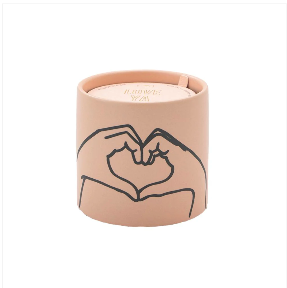 a light pink ceramic candle with a black line design of hands forming a heart, with a gold foil stamped dust cover.