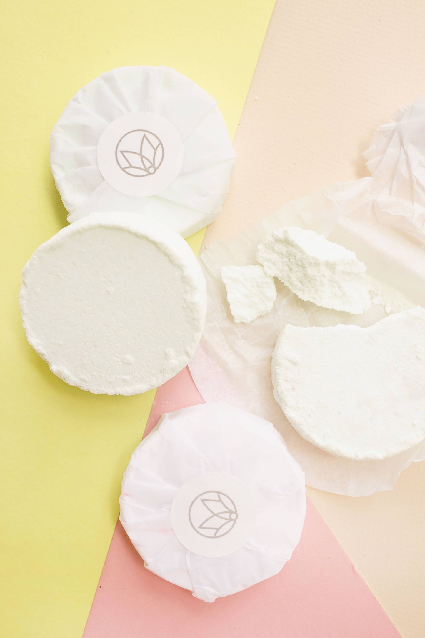 White cotton pads with a logo on a soft pink and yellow background
