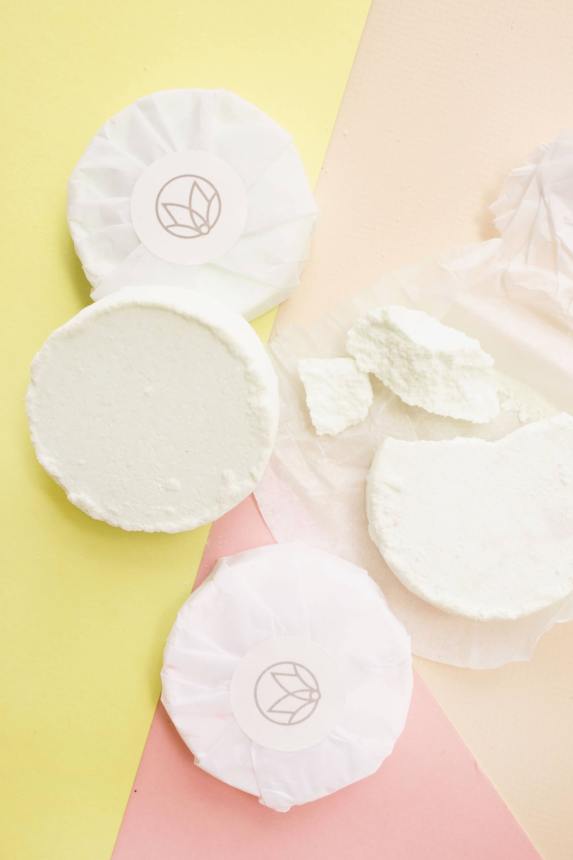 White cotton pads with a logo on a soft pink and yellow background