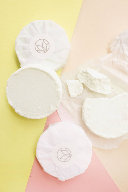 White cotton pads with a logo on a soft pink and yellow background