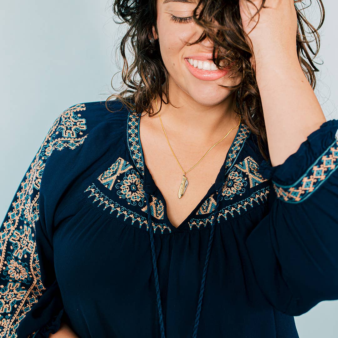 Woman wearing a dark blue embroidered dress with a light background