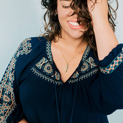 Woman wearing a dark blue embroidered dress with a light background