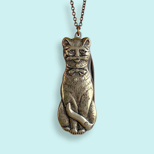 Metallic cat-shaped pendant a chain on a light gray background
