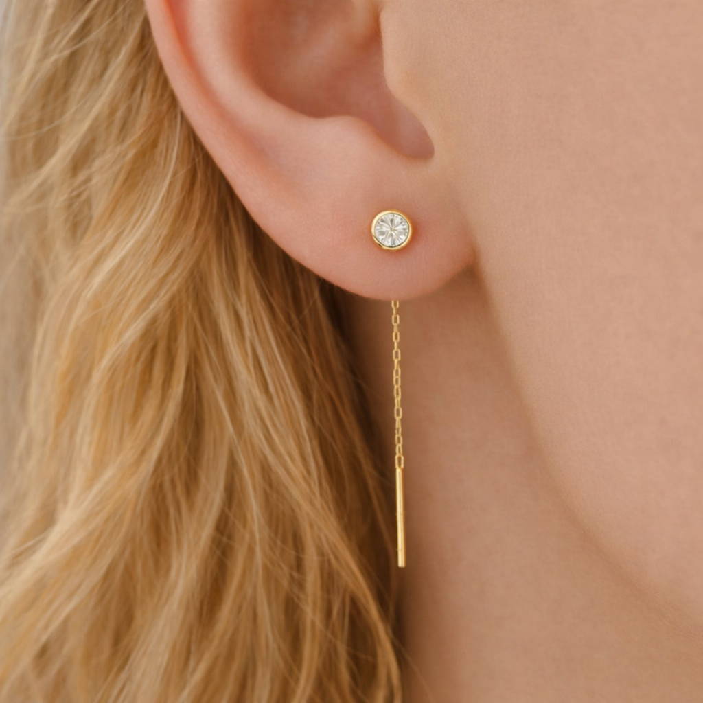Gold earring with a chain detail worn by a person with blonde hair.