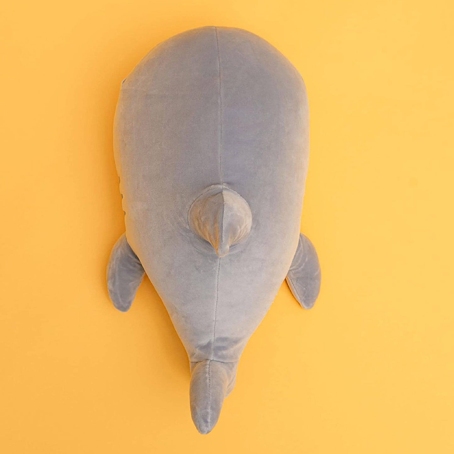 Gray plush shark toy on a yellow background