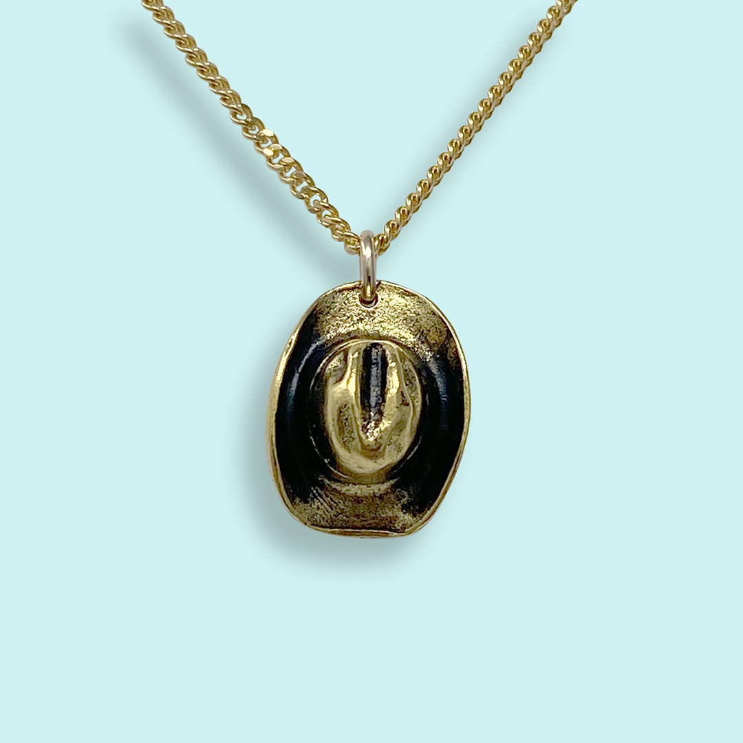 Gold necklace with a black pendant on a light blue background