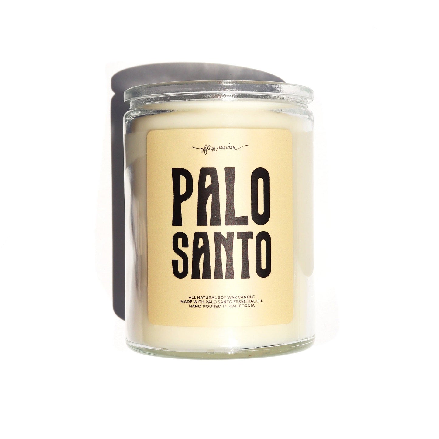 A glass jar candle with cream-colored wax and a beige label reading 'PALO SANTO' in bold black letters. The candle is shown with a dark gray lid and a black side tab, set against a plain white background.