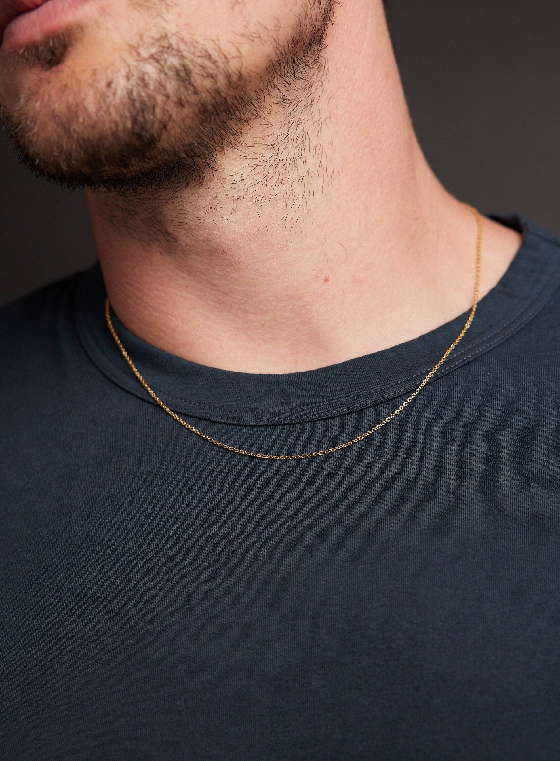 Man wearing a gold necklace against a dark background
