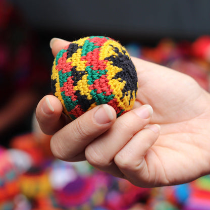 Hand holding a multicolored textured ball against a blurred colorful background
