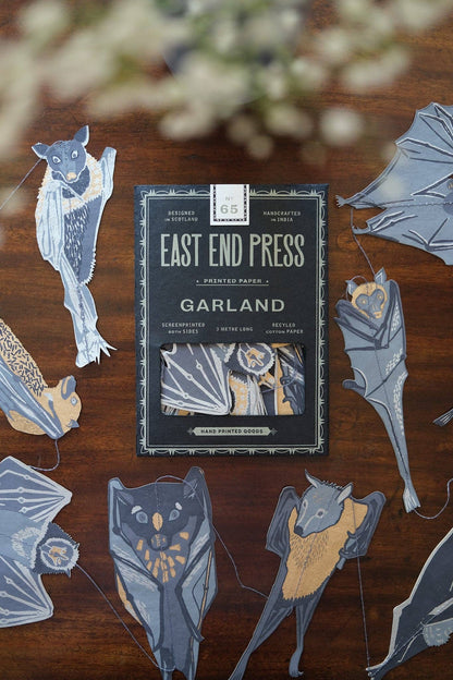 Pack of 'Garland' by East End Press on a wooden surface with decorative cutouts.