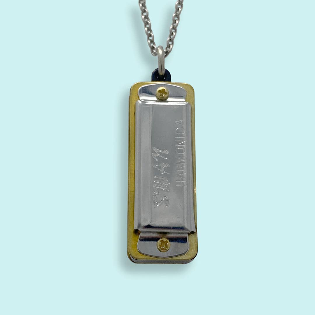 Metallic harmonica pendant on a chain against a light blue background