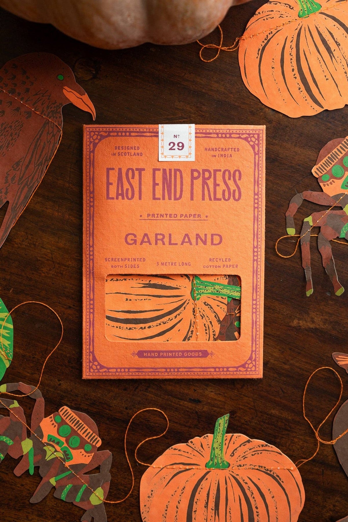 East End Press Garland package on a wooden surface with decorative pumpkins and ribbons.