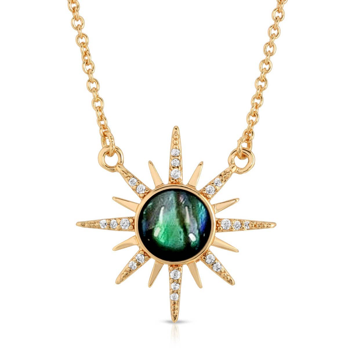 A gold sunburst pendant necklace featuring a round iridescent green labradorite stone in the center, accented with small clear pavé stones along the sun rays, shown on a white background.