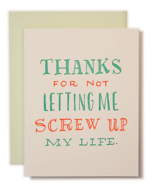 Card with humorous text 'Thanks for not letting me screw up my life' on a beige background with a green envelope.
