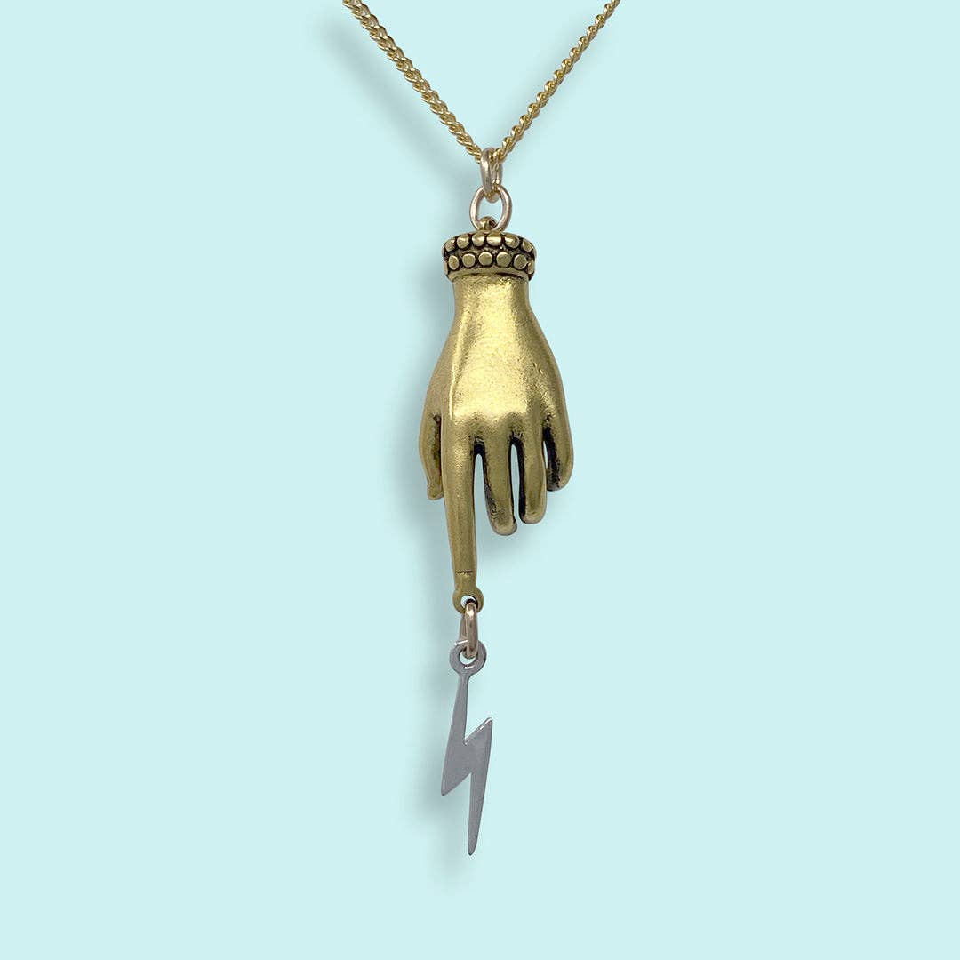Necklace with a gold hand pendant and silver lightning bolt charm on a light blue background