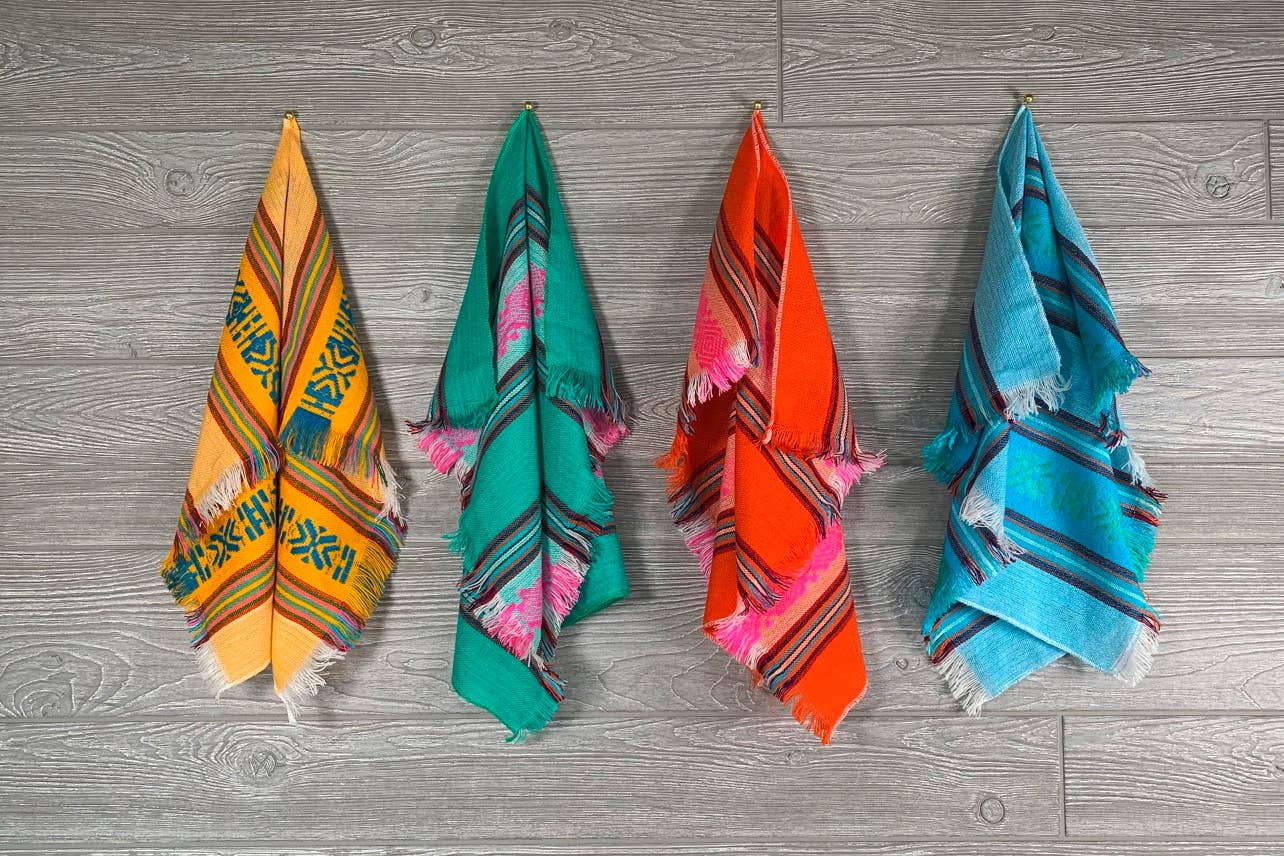 Four colorful towels hanging on a wooden surface