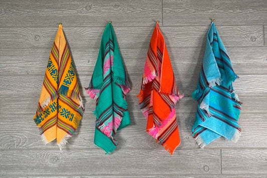 Four colorful towels hanging on a wooden surface