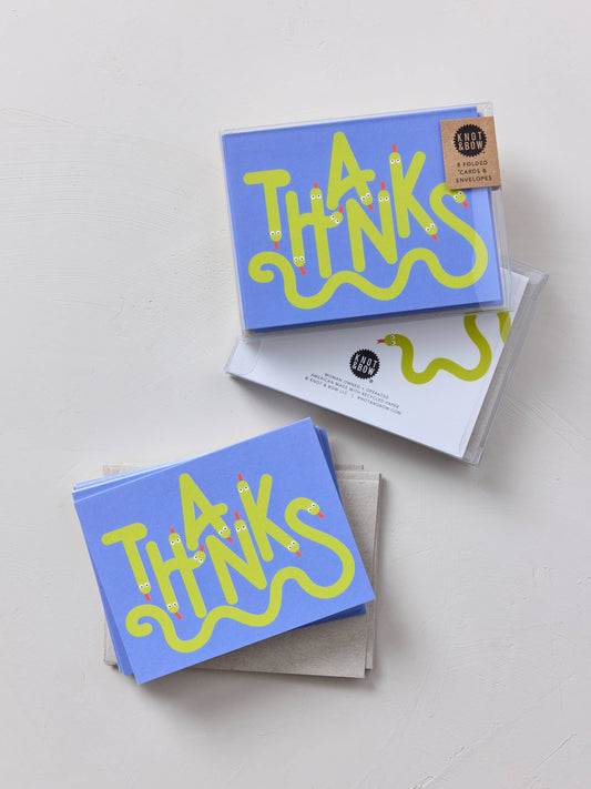 Stack of blue greeting cards with yellow 'THANKS' text on a light gray background
