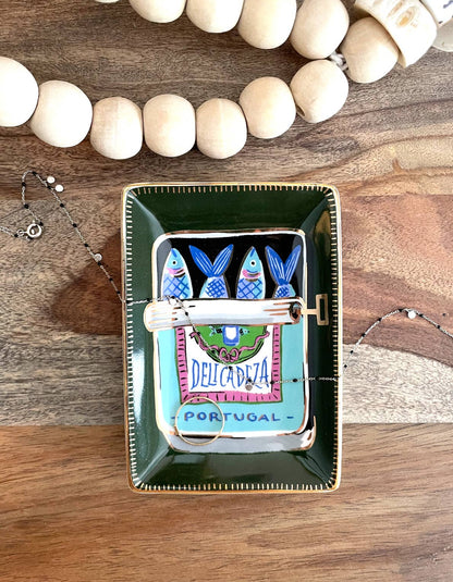 Decorative jewelry tray with fish design on a wooden surface
