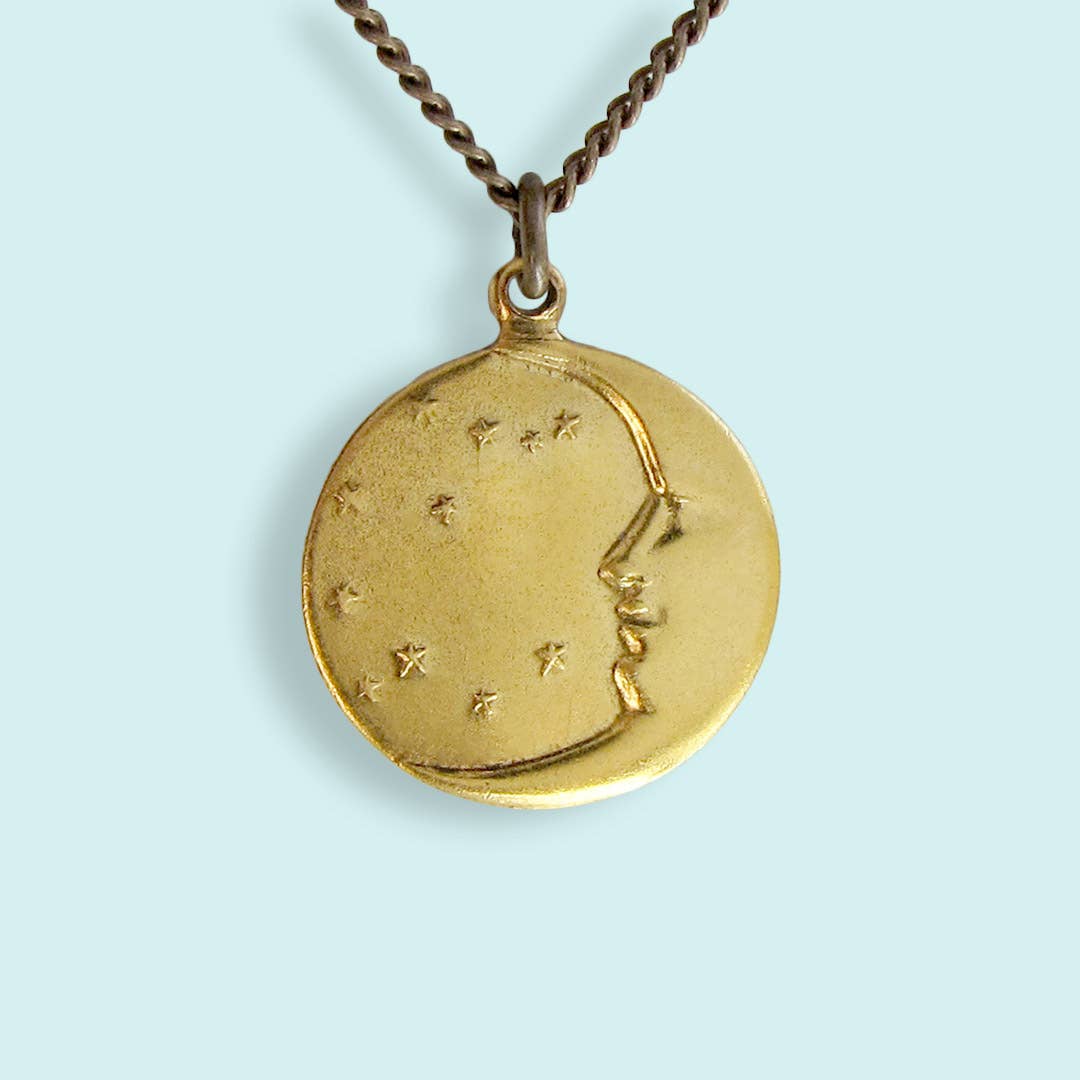 Gold pendant with astrological design on a light blue background