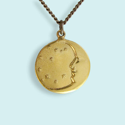 Gold pendant with astrological design on a light blue background