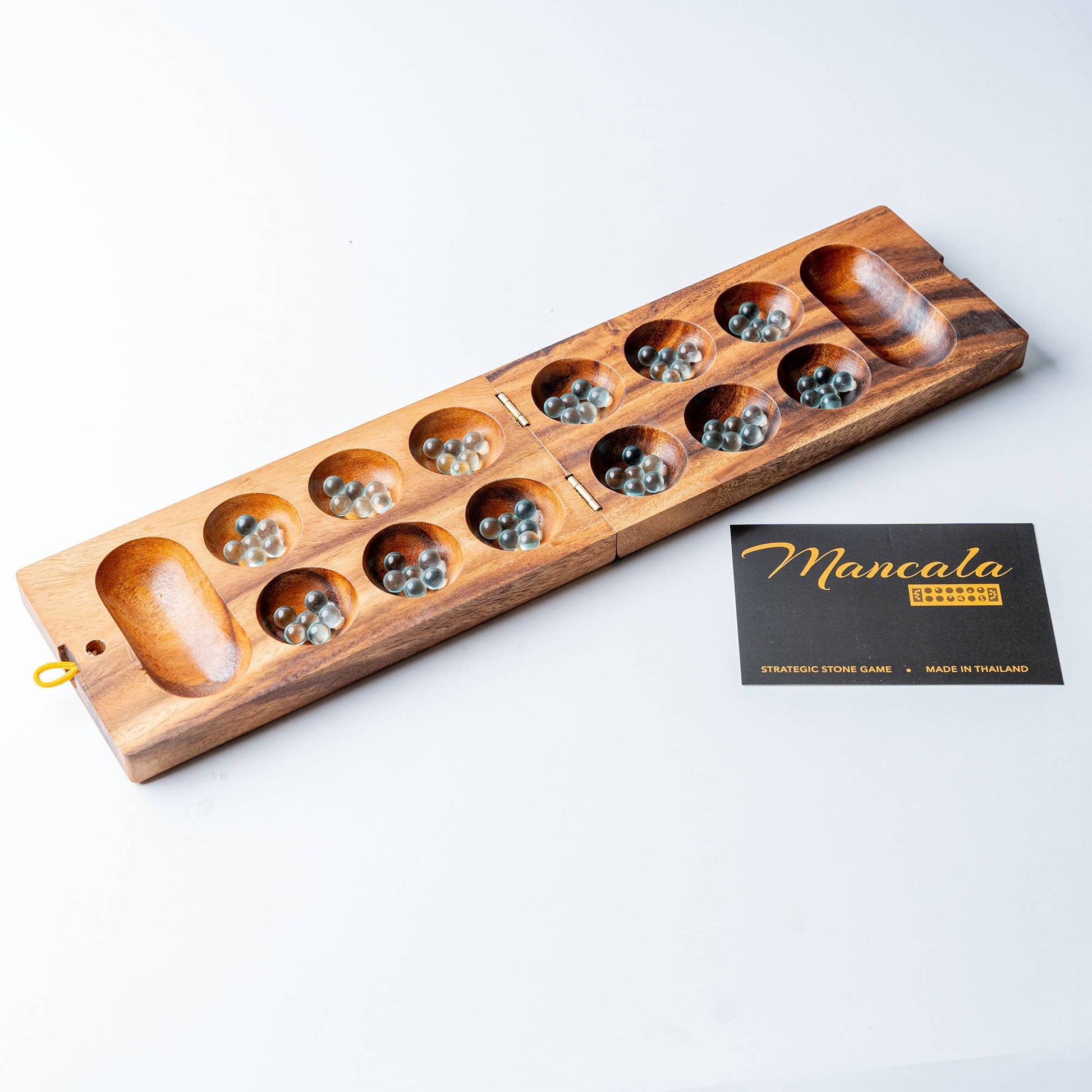 Wooden mancala game set on a white background with a card labeled 'Mancala'.