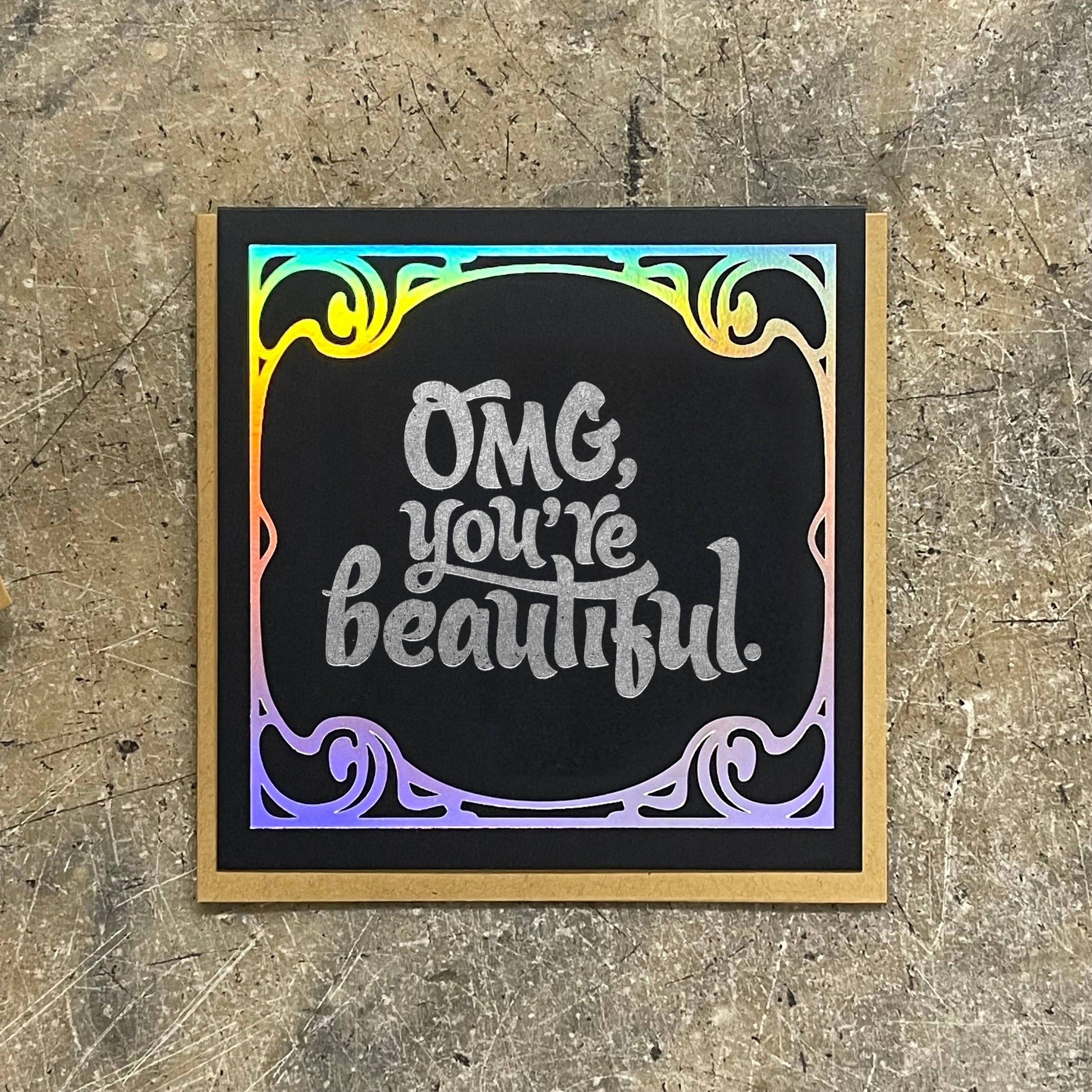 Card with 'OMG, you're beautiful.' text on a textured surface