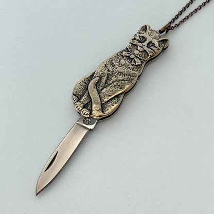 Metallic cat-shaped knife with a chain on a light gray background