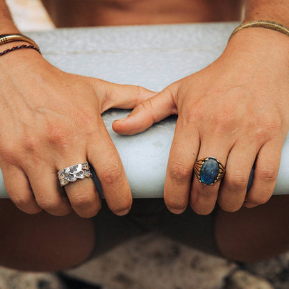 Two hands holding a cylindrical object, each wearing a ring.