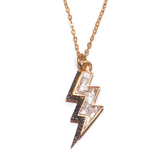 A gold vermeil necklace with a pendant shaped like a bolt, adorned with black and white diamonds.