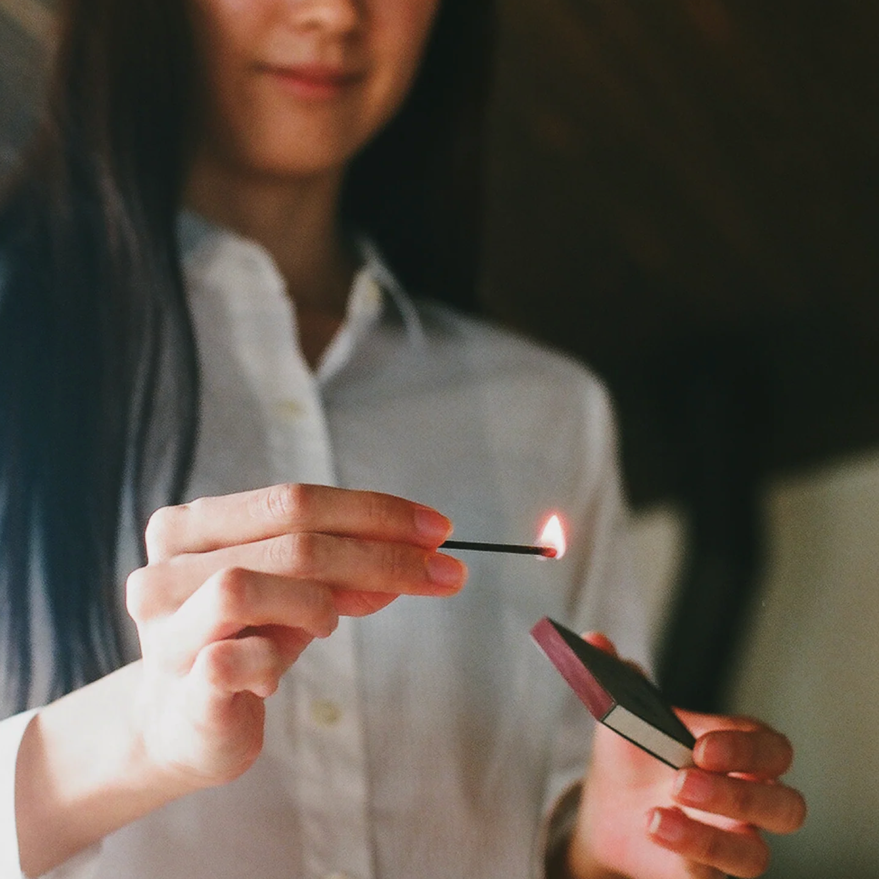 Person lighting a match with a lighter, blurred background
