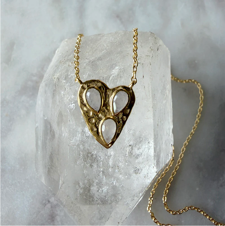 Gold heart-shaped necklace on a clear crystal block