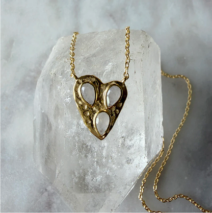 Gold heart-shaped necklace on a clear crystal block