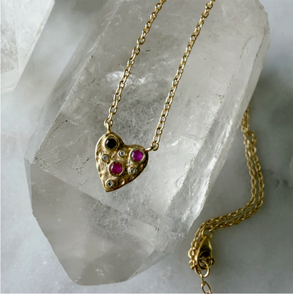 Gold heart-shaped necklace with gemstones on a crystal background