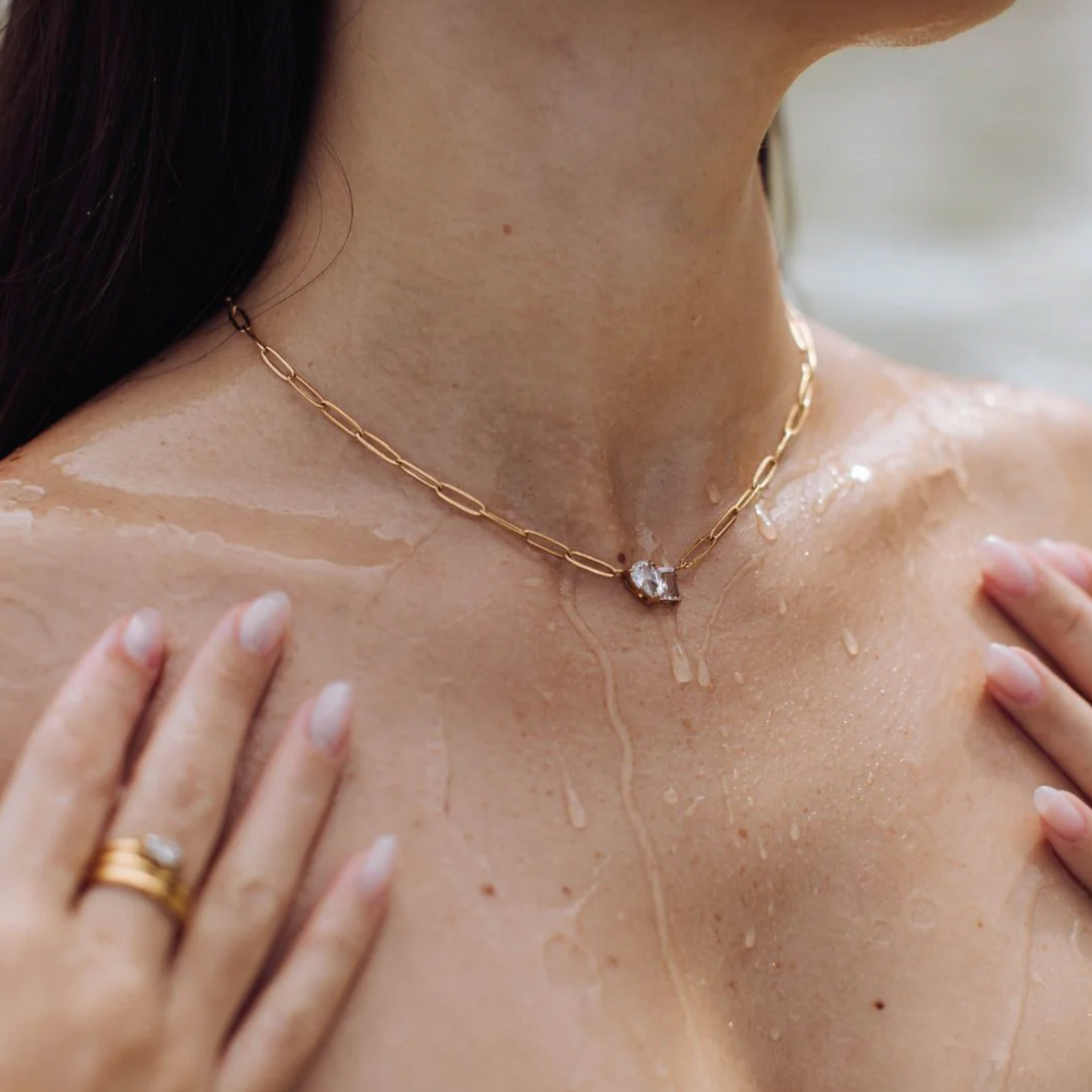 Close-up of a person wearing a gold necklace with a diamond pendant.