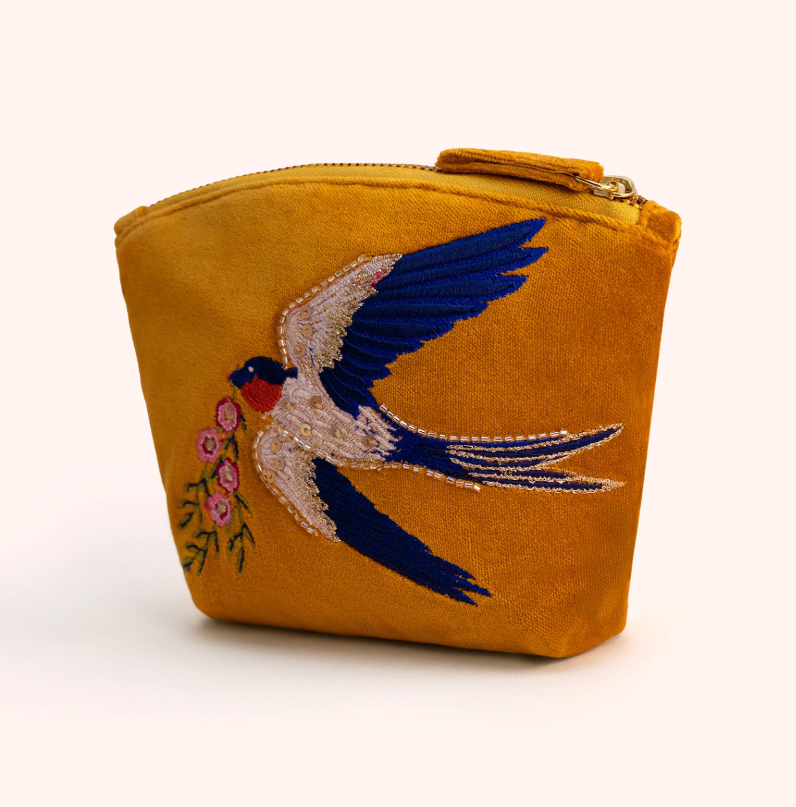 A mustard yellow velvet zippered pouch featuring an embroidered swallow bird carrying pink flowers, set against a plain off-white background.