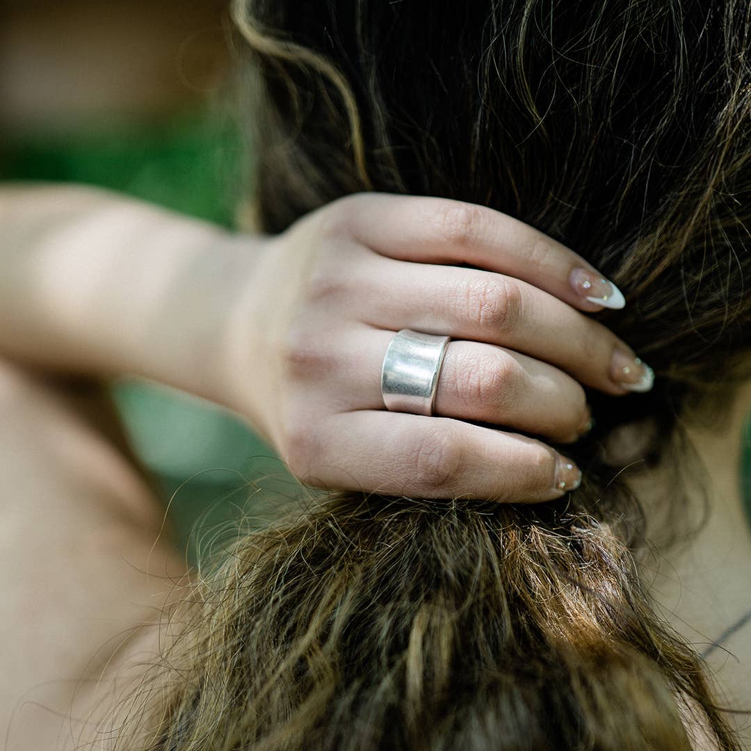 Hand with a silver ring holding hair, blurred background