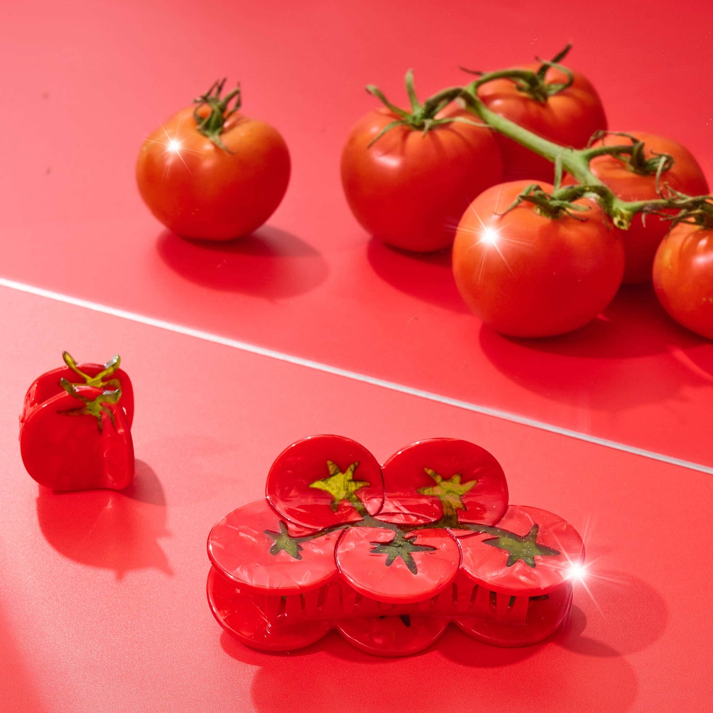 Red tomatoes on a red surface with a red plastic hair claw shaped like a tomato.