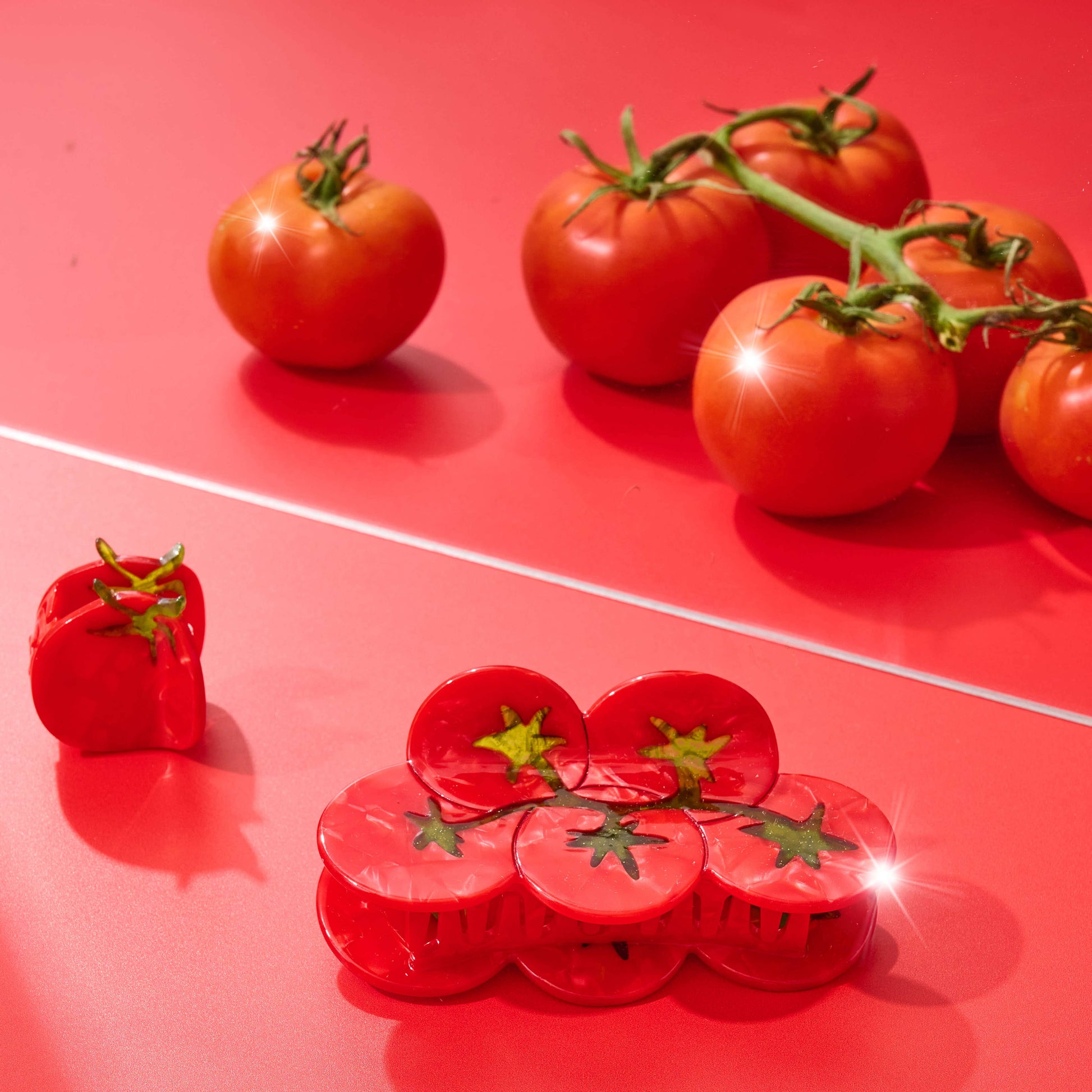 Red tomatoes on a red surface with a red plastic hair claw shaped like a tomato.