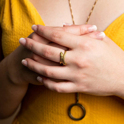 Close-up of hands with a gold ring and necklace against a yellow background