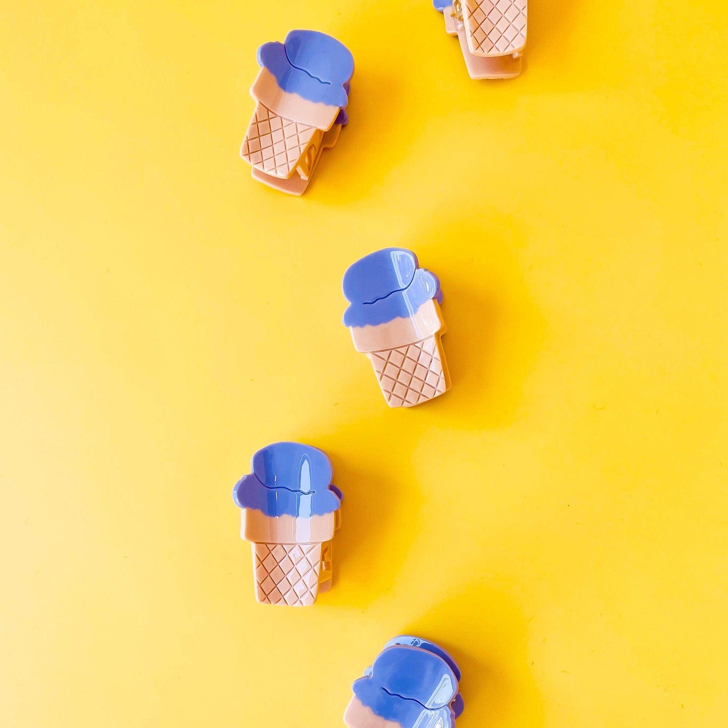 Ice cream cone-shaped containers with blue lids on a yellow background