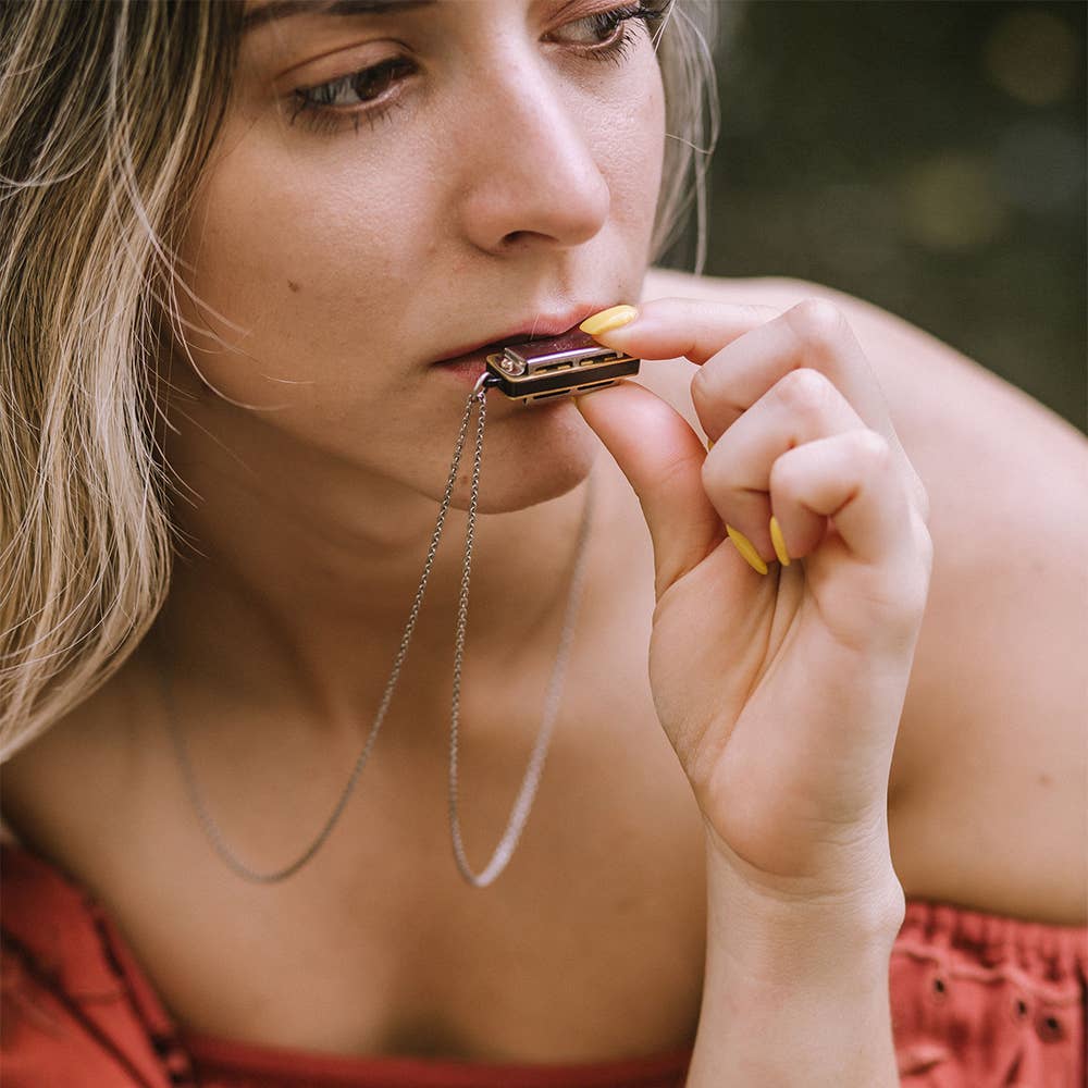 Woman holding a harmonica to her mouth with a blurred background