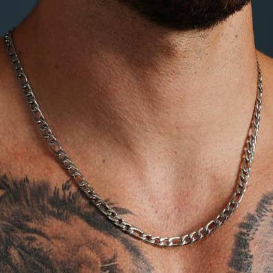 A close-up of a man's neck and upper chest wearing a thick silver-toned curb chain necklace.