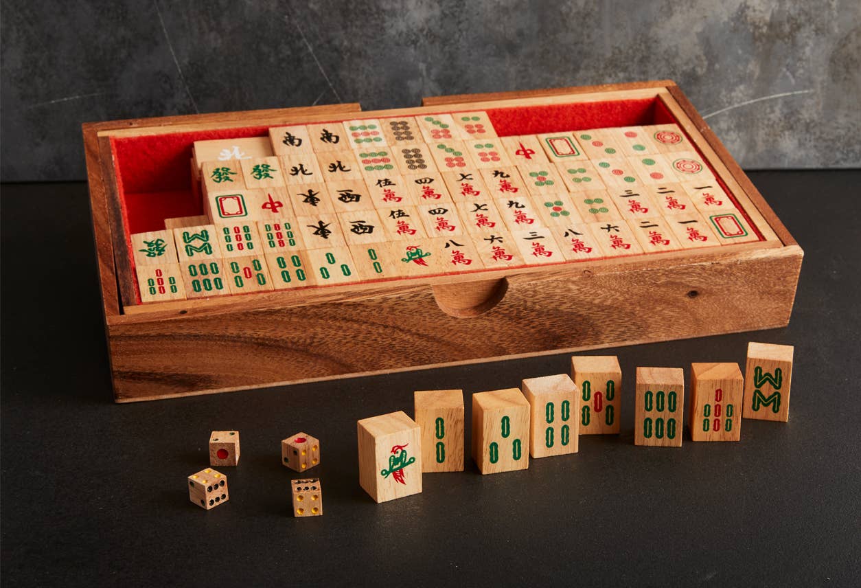 Wooden Mahjong set with tiles and box on a dark surface