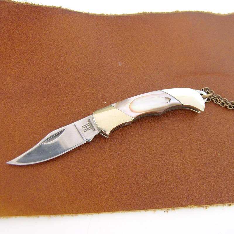 Folding knife with a chain on a brown leather surface