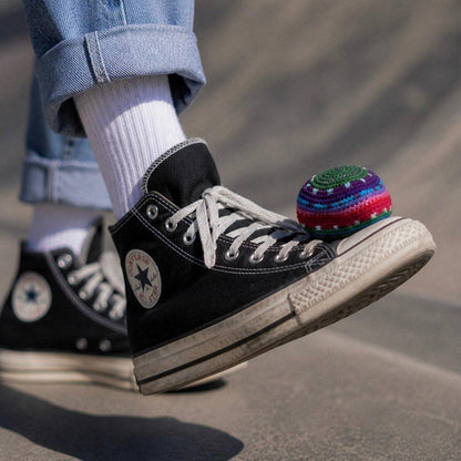 Person wearing black Converse sneakers with a colorful ball on a blurred background